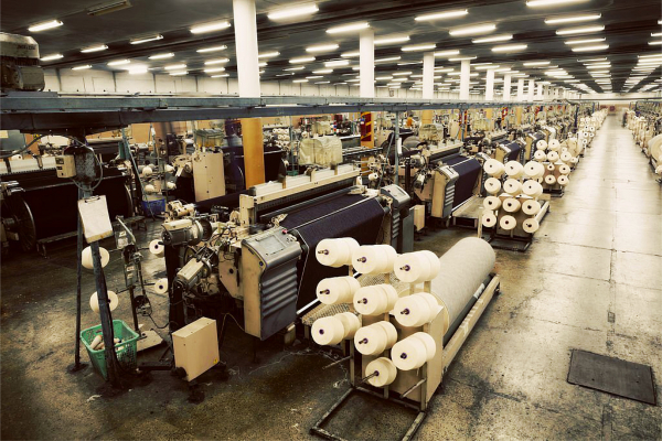 Tissu en cours de tissage sur métiers à tisser à jet d'air dans une grande unité de tissage textile de Denim
